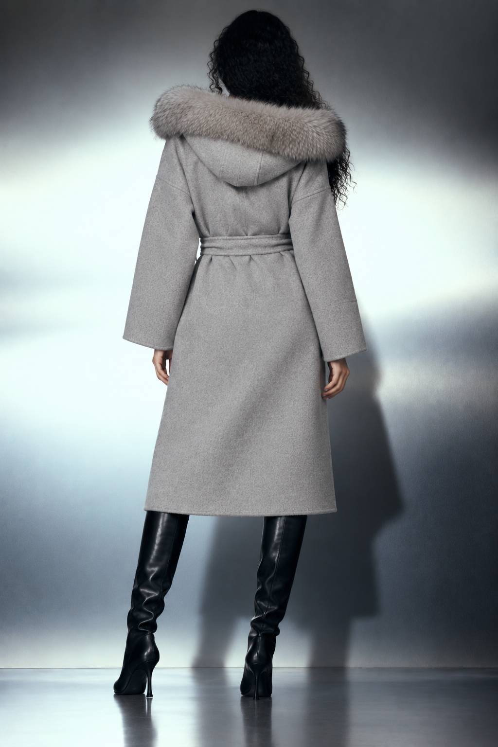 The Samara Long Coat — long manteau gris à capuche fourrure, porté plein pied de dos